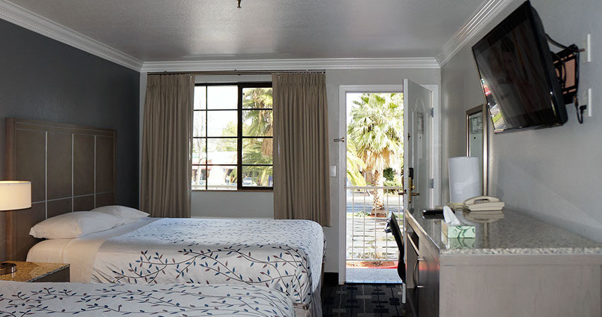 Photo showing 2 queen beds, large viewing windows, writing desk, television and direct dial phone.