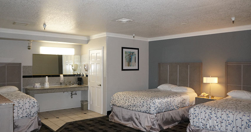 Photo showing 3 queen beds, spacious room with night stands and lamps.